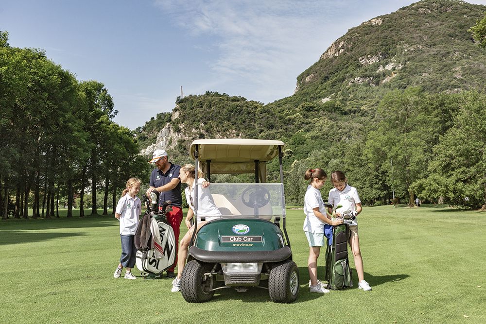 een groep mensen rond een golfkarretje op een golfbaan